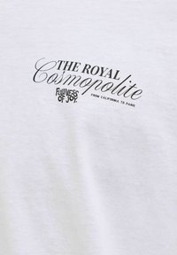 Λευκό ύφασμα με μαύρο κείμενο που αναγράφει «The Royal Cosmopolite», «Fullness of Joy» και «From California to Paris» σε διάφορες γραμματοσειρές.