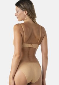 Ensemble de lingerie couleur chair avec un dos lisse, des bretelles ajustables et un tissu doux avec un léger éclat.