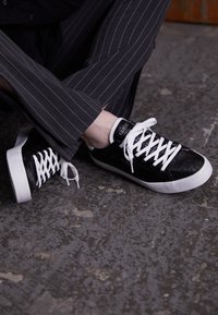 Sneaker nera con tomaia texturizzata, lacci bianchi e suola in gomma bianca. Presenta il marchio 'Guess' sulla linguetta e un design elegante e a profilo basso.