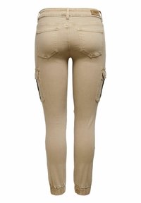 Pantalones cargo beige con un corte ajustado, que cuentan con bolsillos laterales, puños elásticos y una textura suave. Detalles en el bolsillo trasero incluidos.