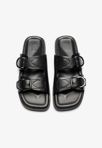Sandalias de cuero negro con dos correas anchas y hebillas ajustables, que cuentan con una plantilla texturizada y una suela plana rectangular.