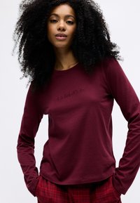 Langærmet burgunder skjorte med tonalt broderet "Calvin Klein" logo, lavet af blødt stof med en afslappet pasform og rund halsudskæring.