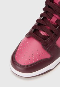 Maroon and pink leather sneaker with perforated toe box, dark laces, and white sole. Smooth texture with stitch accents.