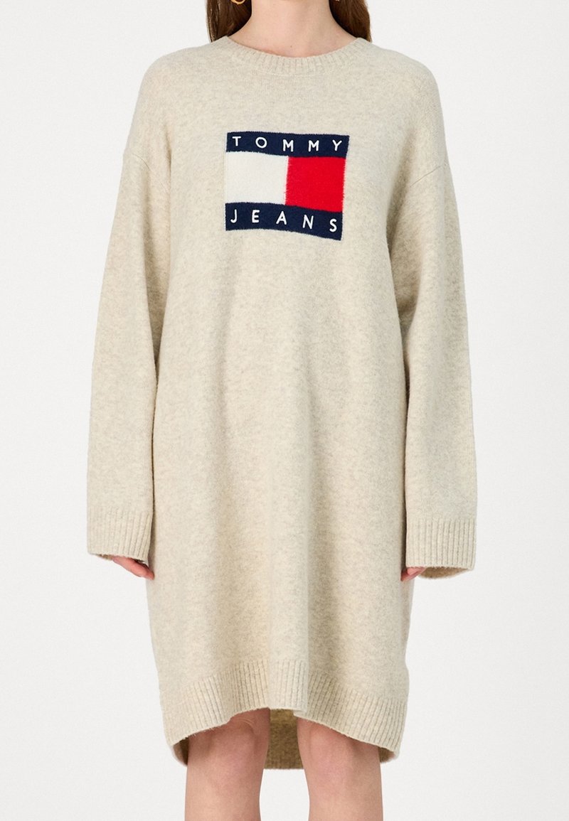 Robe pull beige à manches longues avec poignets et ourlet côtelés, avec un patch logo rectangulaire Tommy Jeans sur la poitrine.