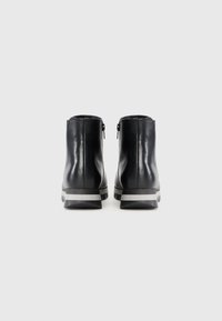 Stivali ankle in pelle nera con texture liscia, dotati di zip posteriore e suola in gomma grigia con strisce per una migliore aderenza.