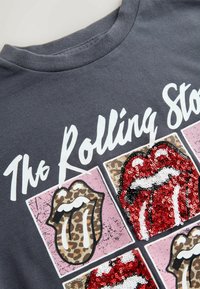 Szary T-shirt z okrągłym dekoltem z ozdobnym, cekinowym wzorem ust zespołu Rolling Stones w kolorze czerwonym i czarnym, z akcentami w panterkę na jasnym tle.