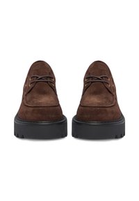 Brūnas zamšādas mežģīņu kurpes ar apaļu purngalu, kontrastējošu melnu gumijas zoli un dekoratīvām zelta krāsas acīm. Plakanas auklas un šūšanas detaļas.