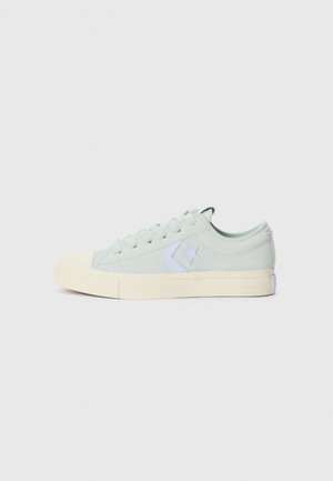 Jasnozielony niski sneaker Converse z białym logo w kształcie gwiazdy i kremową gumową podeszwą, widziany z boku na jednolitym tle.