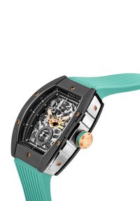 Orologio di lusso con quadrante scheletrato trasparente, cassa nera, cinturino in gomma turchese e dettagli in oro rosa su corona e lancette.