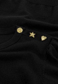 Zwarte gebreide trui met drie decoratieve gouden knopen: een bloemontwerp met parel, een ster en een hartvorm. Zachte textuur, klassieke ronde hals.