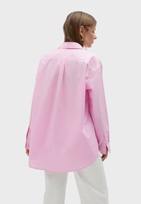 Rosa Langarmhemd mit lässiger Passform, Knopfmanschetten, Kragen und abgerundetem Saum, aus glattem Baumwollstoff.
