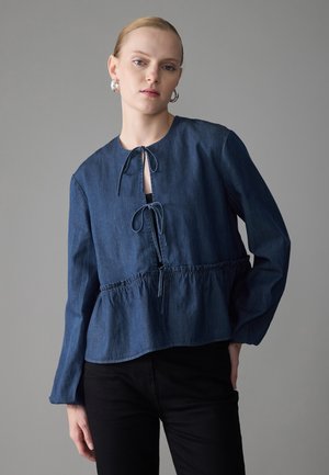 Donkerblauwe denim blouse met een ronde hals, striksluiting en geplooide taille. Lange mouwen en een ontspannen pasvorm benadrukken het casual ontwerp.