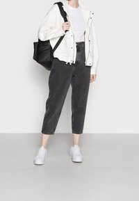 Černé džíny do půli lýtek, bílý bavlněný tričko a bílá podšívková bunda. Doplněno bílými teniskami a černým batůžkem.