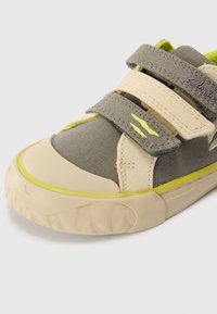 Szare sneakersy z tkaniny z beżowymi akcentami i rzepami, z teksturowaną gumową podeszwą i jaskrawozielonymi detalami po bokach.