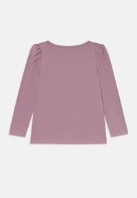 Jente sin langermede mauve topp med lett puffede skuldre, rund halslinning og enkel rett kant, lagt flatt på en hvit bakgrunn.