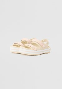 Sandalias ligeras en rosa pálido y crema, con correas dobles, una plantilla texturizada y suela blanca con un sutil acento rosa.