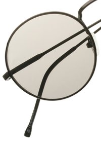 Pyöreät aurinkolasit tummanharmailla linsseillä, mustassa metallikehyksessä, ohuilla varsilla ja hienovaraisella yksityiskohdalla temppeleissä. Rakennepintaiset kumikorvatyynyt.