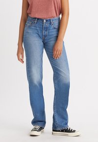 Lichtblauwe denim jeans met een rechte pasvorm, vervaagde afwerking en vijf-pocket stijl. Gedragen met zwarte canvas sneakers.