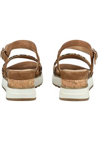 Brown suede sandals with cork accents, open heel, adjustable strap, white rubber sole, and smooth interior lining visible from the back view.
