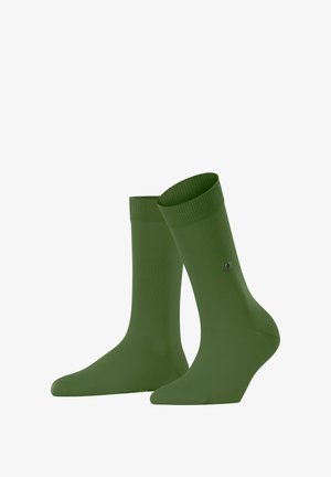 Ein Paar grüne Socken, aufrecht präsentiert, die die glatte Textur und die gerippten Bündchen zeigen, mit einem kleinen Logo, das an der Seite sichtbar ist.