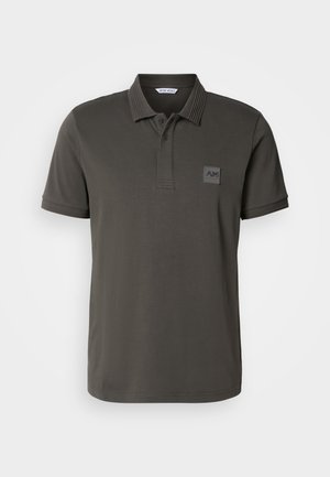 Dark green polo shirt made of cotton, featuring a ribbed collar, three-button placket, and a decorative logo patch on the chest.