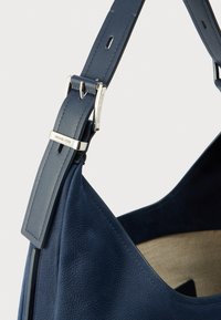 Navy leather shoulder bag with a textured finish, featuring a silver-tone hardware accent and adjustable strap for functionality.