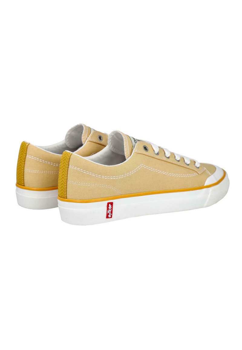 Par de zapatillas bajas de lona beige con cordones blancos, suelas de goma blancas, ribete amarillo y etiqueta con el logo rojo de Levi's en el lateral.