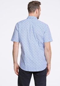Camisetta a maniche corte in tessuto azzurro chiaro, con un delicato motivo floreale. La parte posteriore presenta un colletto classico e un orlo arrotondato.