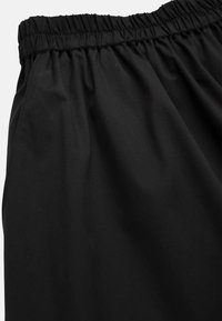 Black elastic waistband shorts made from a lightweight, smooth fabric. Features a gathered waist and subtle stitching details.
