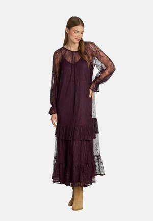 Vestido largo en capas de un profundo color púrpura con mangas largas de encaje transparente y un dobladillo con volantes. Presenta un corte relajado y una tela texturizada.