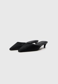Schwarze spitze Mules mit niedrigem Absatz, aus strukturiertem Material, mit offenem Rücken und glatter Innenauskleidung für zusätzlichen Komfort.