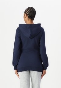 Marineblauwe hoodie met een ontspannen fit, voorzien van lange mouwen en een afgeronde zoom, gemaakt van zachte, gestructureerde katoen.