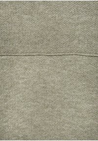 Hellgrüner texturierter Stoff mit einem gestrickten Muster, das subtile Farbvariationen und ein horizontales Nahtdetail aufweist.