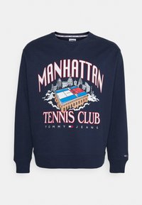Felpa navy con grafiche "MANHATTAN TENNIS CLUB" in rosso e bianco, accompagnata da un design di campo da tennis blu e rosso e logo Tommy Jeans.