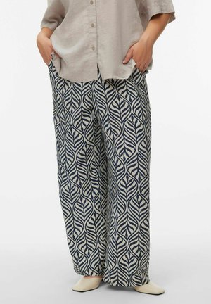 Bukser med vide ben og bladmønster i creme og marineblå, lavet af blødt stof. Sat sammen med en lysebeige kortærmet skjorte.