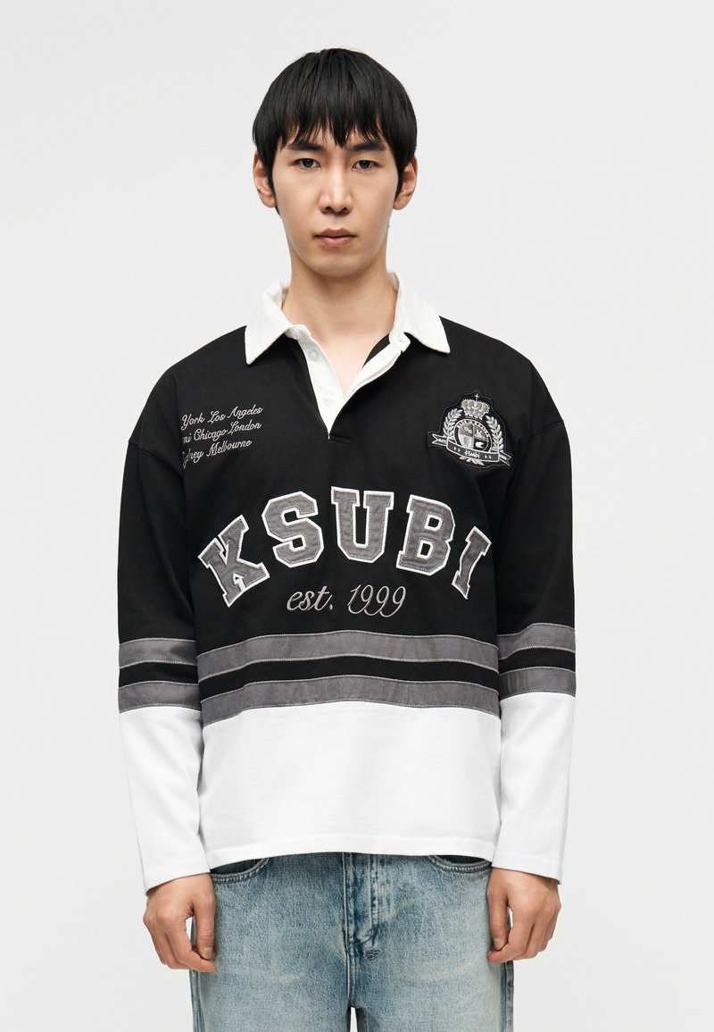 Μακρυμάνικο ράγκμπι μπλουζάκι ασπρόμαυρο με κεν τημένο λογότυπο, οριζόντιες ρίγες και κείμενο. Μαλακό βαμβακερό υλικό, άνετη εφαρμογή.