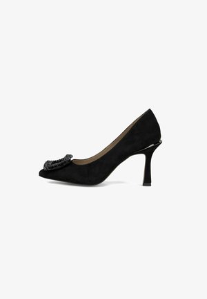 Chaussure à talon haut en daim noir avec un bout pointu et un accent décoratif en perles noires à l'avant. Dispose d'un talon effilé et d'une texture lisse.