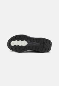Black rubber shoe sole with textured pattern, including a central white component and various protruding lugs for grip and traction.