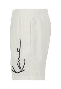 Shorts blancs en tissu léger avec un dessin abstrait en ligne noire sur le côté. Taille élastique avec une coupe décontractée.