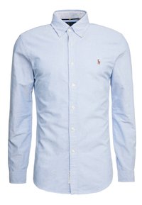 Ljust blå skjorta med knappar, tillverkad av bomull, med en spetsig krage, vita knappar och en broderad logo på vänster bröst.