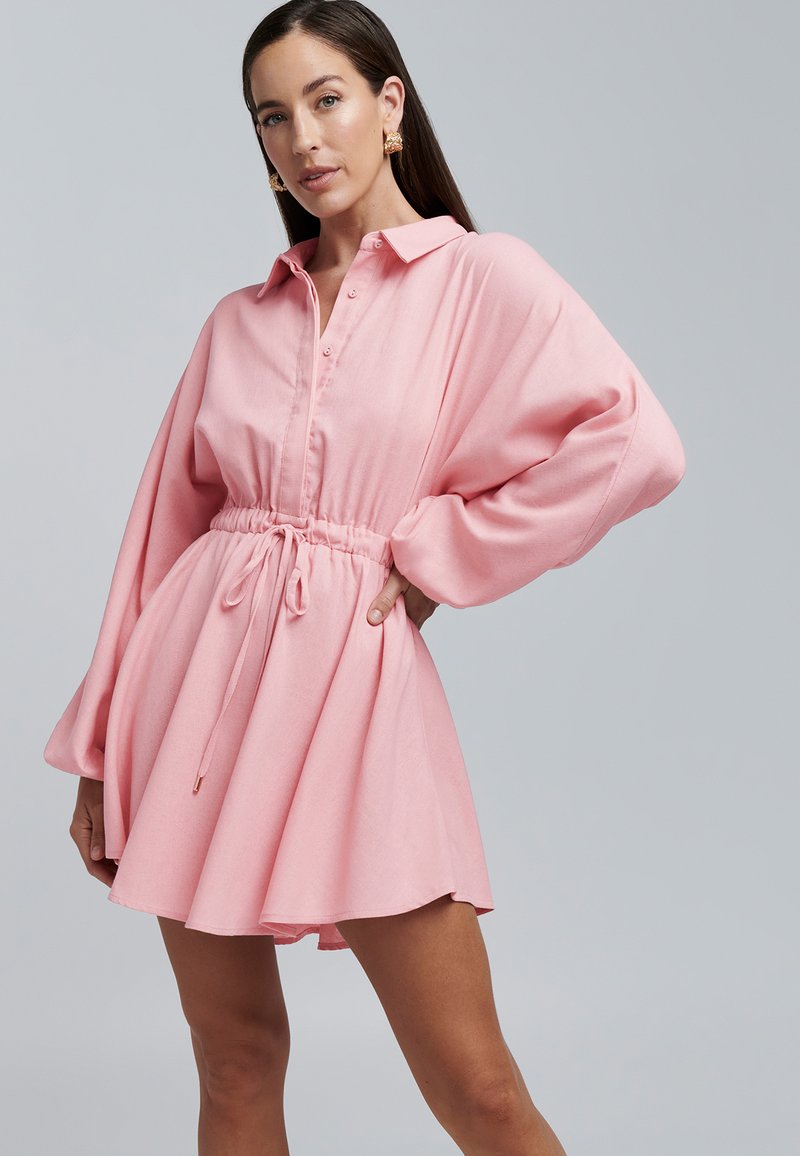 Roze shirtjurk met een kraag, knoopsluiting aan de voorkant, elastische taille en lange, volumineuze mouwen. Glad stof met een zachte textuur.