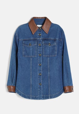 Chemise en denim bleu à manches longues boutonnée avec col et poignets en cuir marron, deux poches poitrine avec rabats à boutons et coutures visibles.