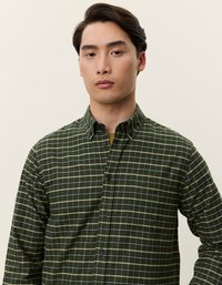 Zaļš pārbaudītu rakstu krekls, izgatavots no mīksta auduma. Tam ir pogu aizdare ar apkakli un garām piedurknēm, akcentēts ar tumšām pogām un baltām režģa līnijām.