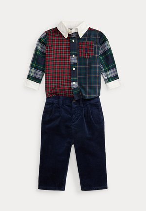 Tenue pour tout-petit avec une chemise à carreaux patchwork à col blanc boutonnée et un pantalon en velours côtelé bleu foncé sur fond blanc.