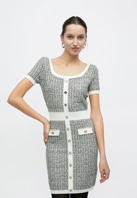 Πλεκτό φόρεμα σε γκρι και λευκό, με κοντά μανίκια, τετράγωνη λαιμόκοψη, κουμπιά μπροστά και δύο τσέπες μπροστά με χρυσές λεπτομέρειες.