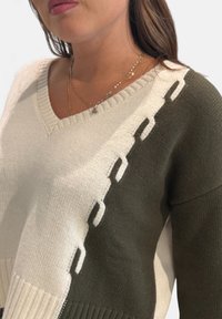 Maglione lavorato a maglia con scollo a V, caratterizzato da sezioni crema e verde oliva, dettagli testurizzati e orlo a coste con dettagli ritagliati.