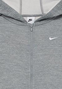 Sweatshirt cinza com fecho, feito de um tecido texturizado, com o logo branco da Nike no peito. Apresenta capuz e fecho frontal.