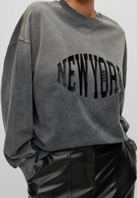 Šedá mikina s černým logem "NEWYORK", s volným střihem, žebrovaným kulatým výstřihem a prošíváním na rukávech.
