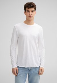 Weißes Langarmshirt mit Rundhalsausschnitt, aus leichtem Stoff, mit einem subtilen Strukturmuster und einer lockeren Passform.