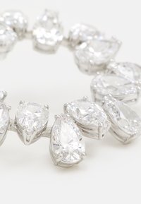 Pulsera de strass con piedras transparentes en forma de pera, engastadas en metal tono plateado. Cada piedra tiene un corte facetado y un acabado pulido.